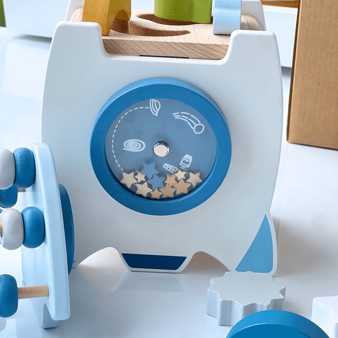 Hublot latéral de la fusée en bois Montessori, montrant l’intérieur et les formes géométriques à encastrer.