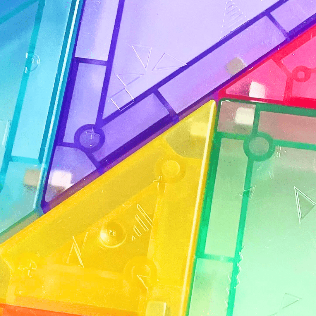 Gros plan sur les textures et formes géométriques des pièces du tangram magnétique Montessori, en plastique transparent coloré.