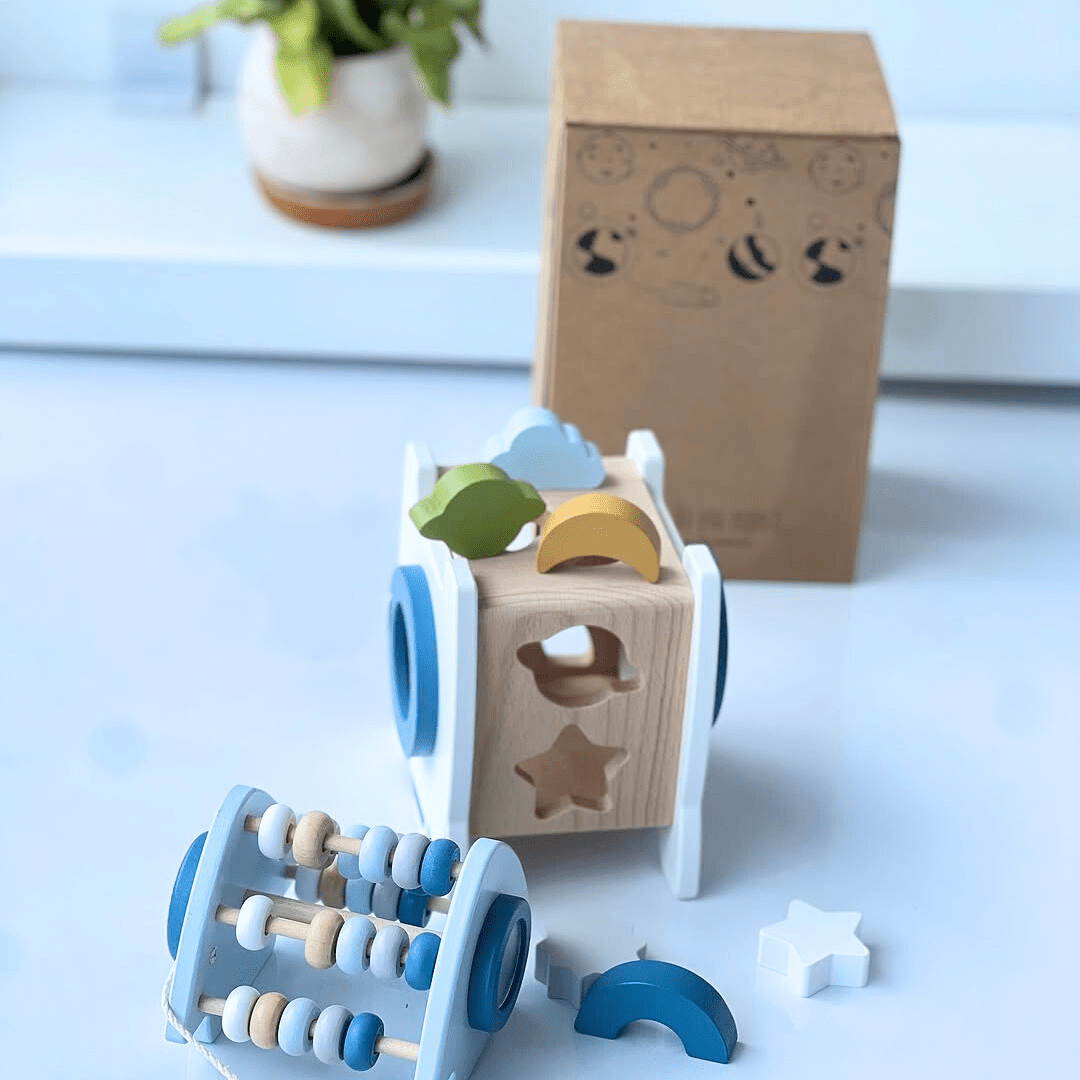 Fusée d’apprentissage en bois avec formes éducatives et boulier, posée à côté de sa boîte d’emballage.