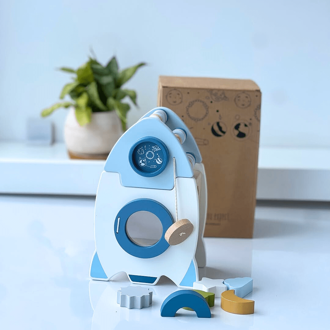 Fusée d’apprentissage en bois pour enfants avec formes à encastrer et packaging en arrière-plan.