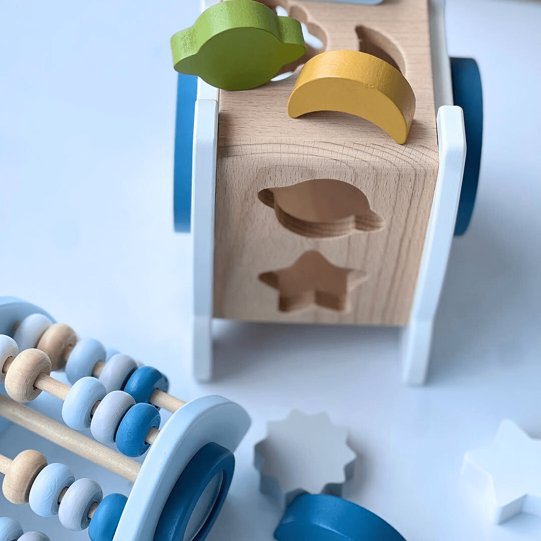 Vue rapprochée des formes en bois colorées à insérer dans la fusée Montessori, avec un boulier assorti.