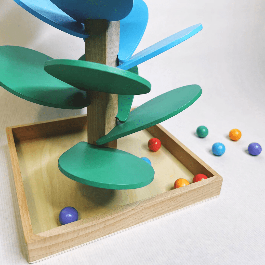 Vue rapprochée de la base de l’arbre arc-en-ciel Montessori avec billes en bois de différentes couleurs