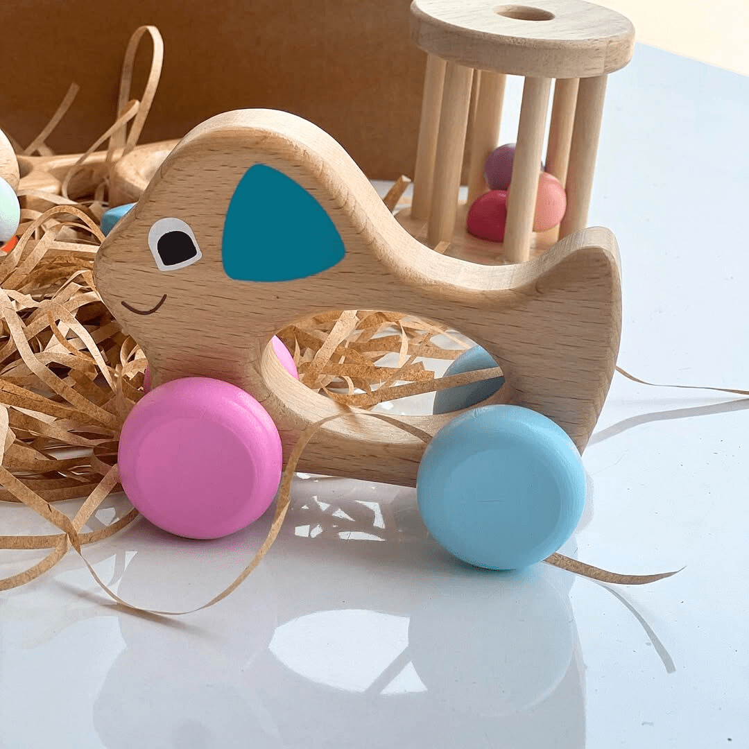 hochet montessori en forme d éléphant avec roues colorées sur surface blanche