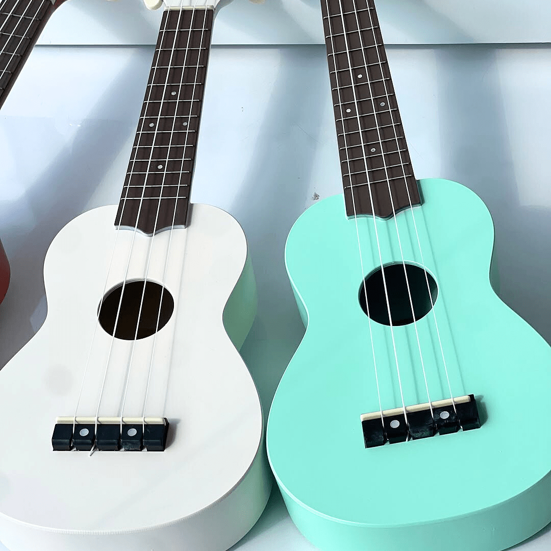 Guitare enfant blanche et verte menthe posées sur une surface blanche