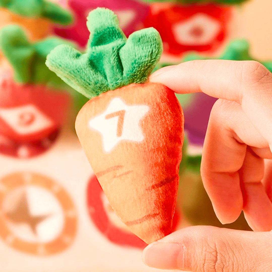 Main d’un enfant tenant une carotte en peluche numérotée, issue d’un jeu éducatif Montessori pour apprendre à compter en s’amusant.